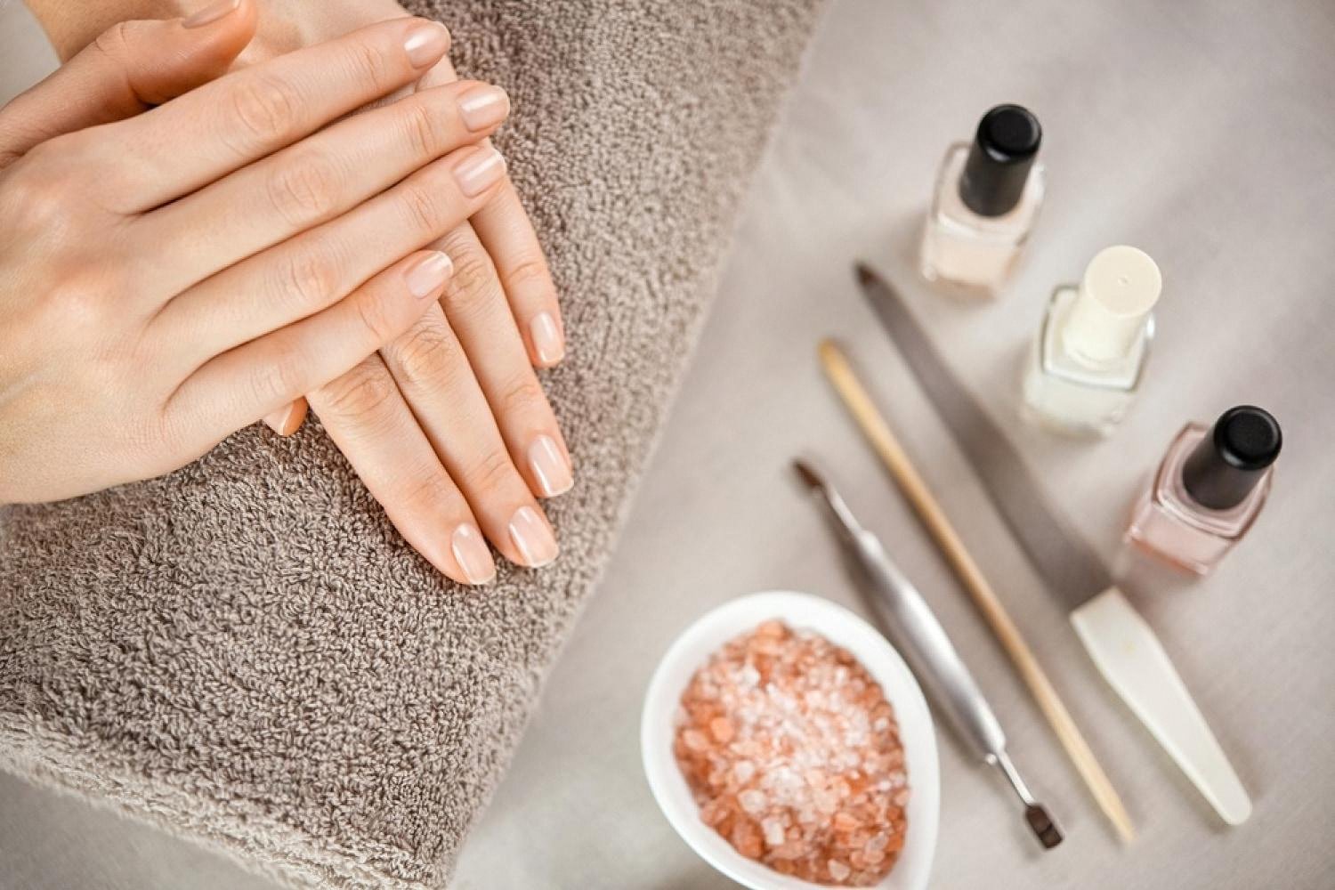 Manicured hands resting on a towel next to nail polish and cuticle tools at a Dubai salon