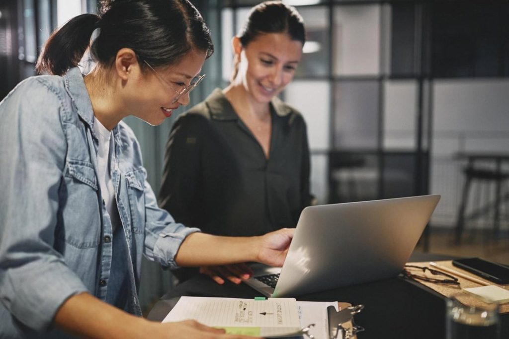 Two colleagues reviewing a UAE domain transfer checklist on a laptop