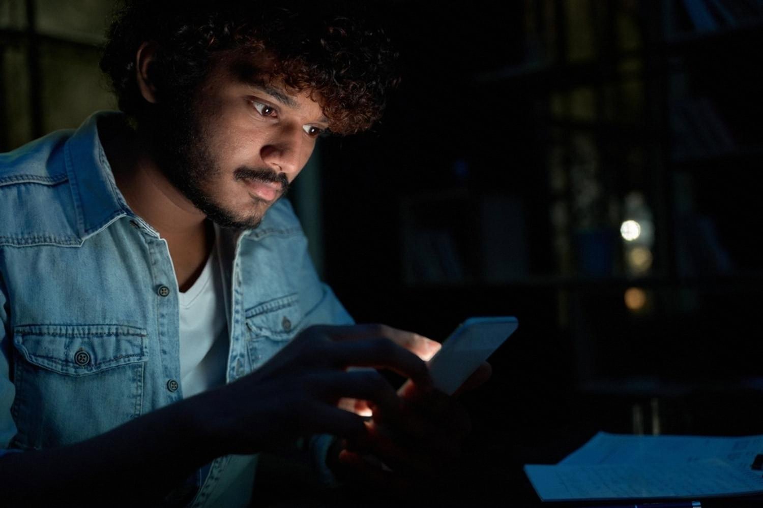 Young man checking event rental listings on a smartphone at night in the UAE